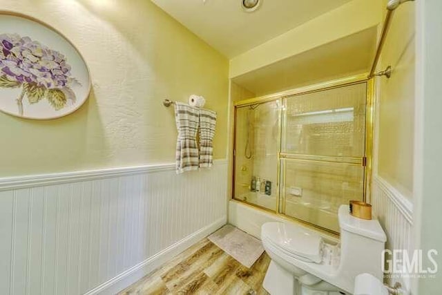 bathroom featuring hardwood / wood-style floors, toilet, combined bath / shower with glass door, and lofted ceiling