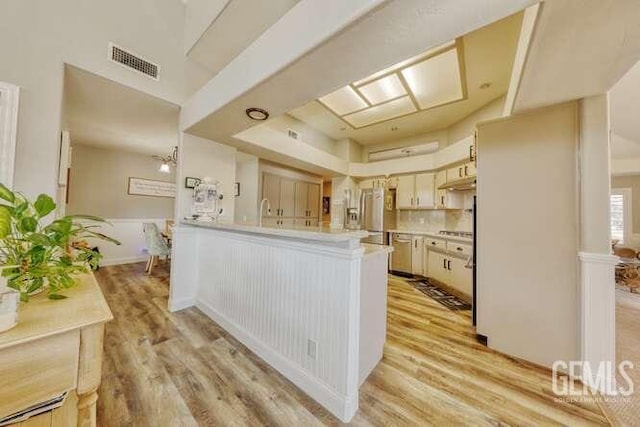 kitchen featuring kitchen peninsula, light hardwood / wood-style floors, stainless steel refrigerator, and tasteful backsplash