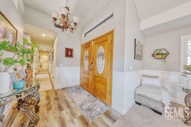 foyer featuring french doors, light hardwood / wood-style floors, and an inviting chandelier