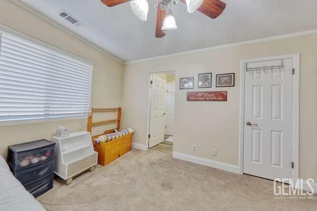 carpeted bedroom with a closet, ceiling fan, and crown molding