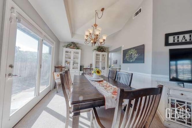 dining room with a tray ceiling, vaulted ceiling, and a notable chandelier