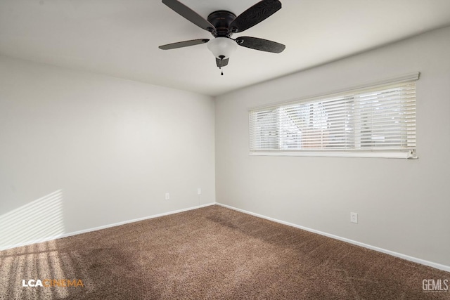 carpeted spare room with a ceiling fan and baseboards