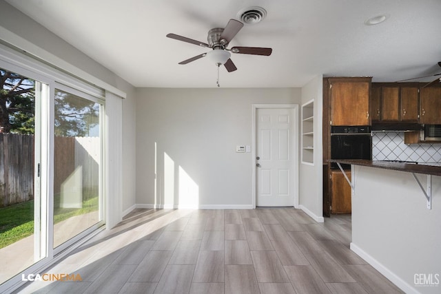 kitchen with baseboards, visible vents, decorative backsplash, dark countertops, and black oven