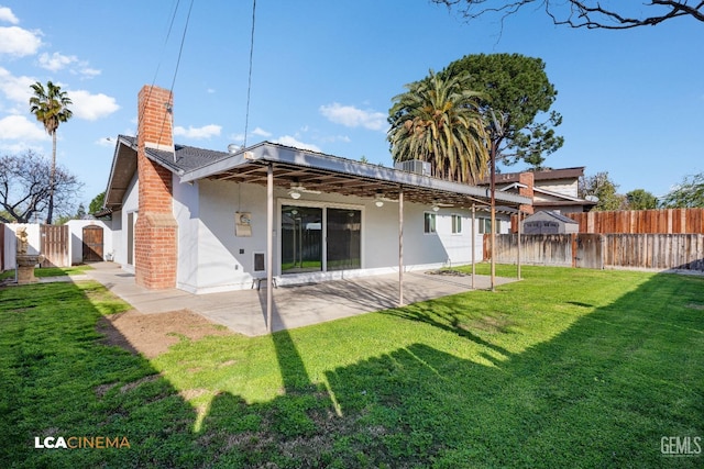 rear view of property with stucco siding, a lawn, a gate, a patio, and fence