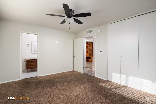 unfurnished bedroom with a closet, visible vents, light colored carpet, and ensuite bathroom