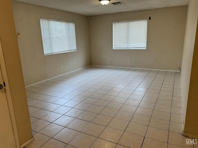 tiled empty room featuring a textured ceiling