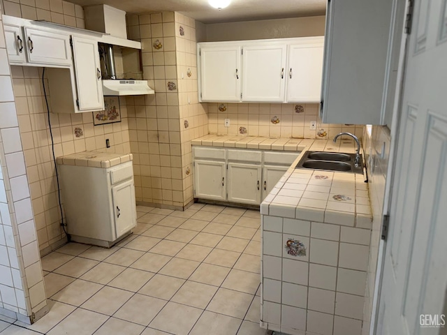 kitchen with white cabinetry, tile counters, sink, and backsplash