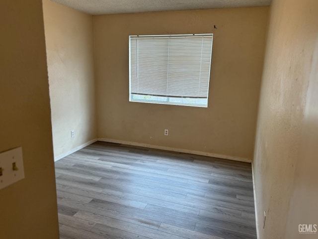 unfurnished room with a textured ceiling and light wood-type flooring