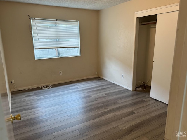 unfurnished bedroom with a closet, wood-type flooring, and a textured ceiling