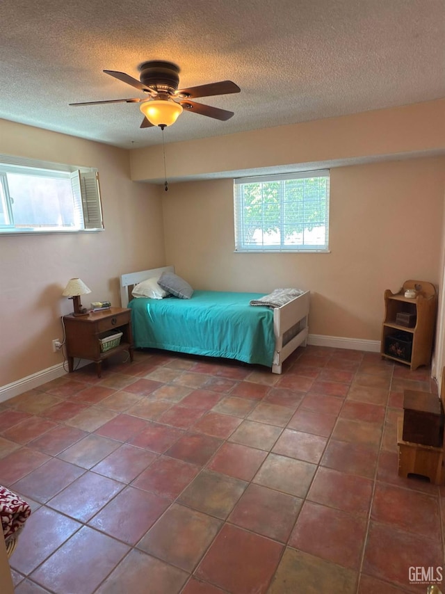 bedroom featuring baseboards, a ceiling fan, a textured ceiling, and tile patterned floors