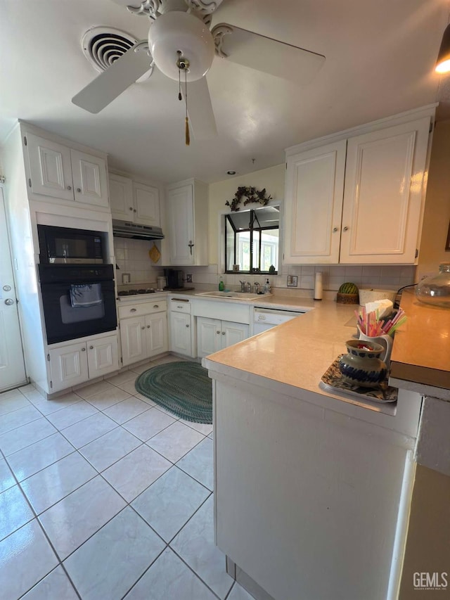 kitchen featuring oven, white cabinetry, backsplash, under cabinet range hood, and visible vents