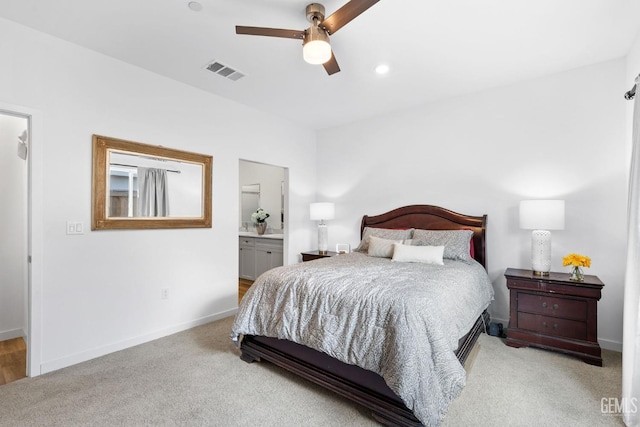 bedroom featuring ceiling fan, connected bathroom, and light carpet