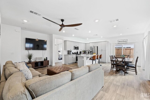 living room with ceiling fan, sink, and light hardwood / wood-style flooring