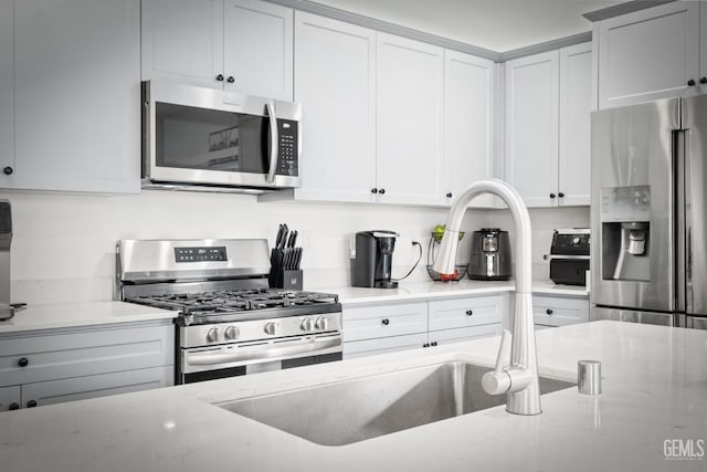 kitchen with light stone counters, appliances with stainless steel finishes, and white cabinets