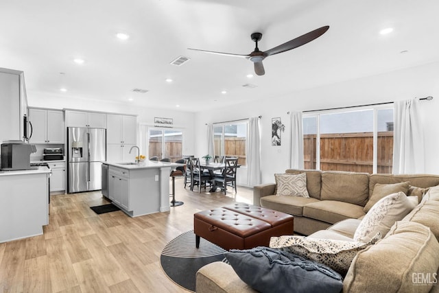 living room featuring sink, ceiling fan, and light wood-type flooring