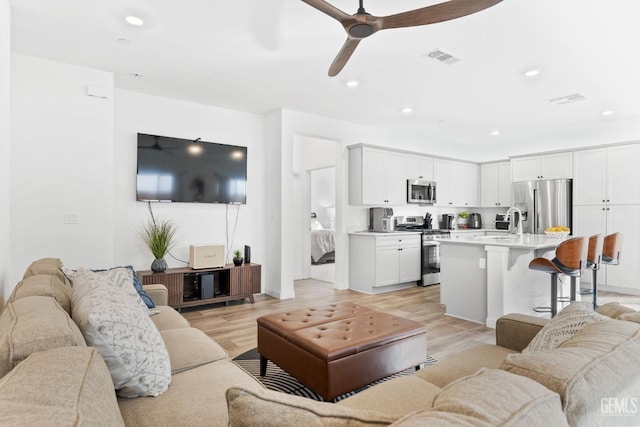 living room with ceiling fan and light wood-type flooring