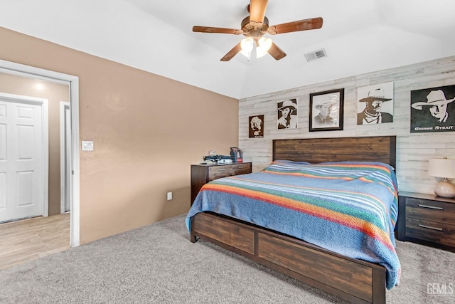 bedroom featuring ceiling fan, light carpet, and wooden walls