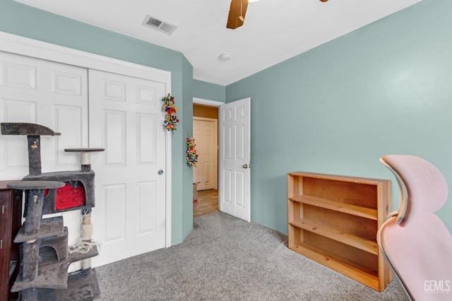 interior space with ceiling fan, light carpet, and a closet