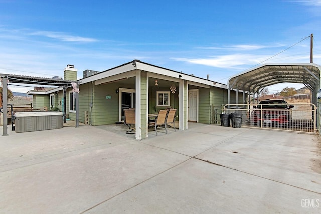 exterior space with a patio, a hot tub, and a carport