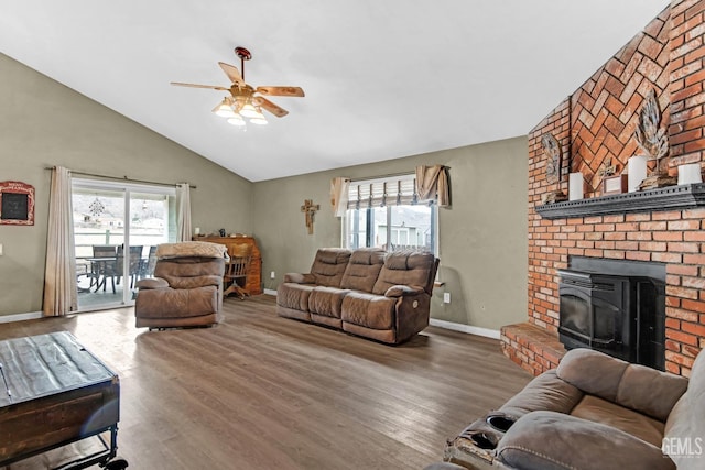 living room featuring hardwood / wood-style floors, vaulted ceiling, a wood stove, and ceiling fan