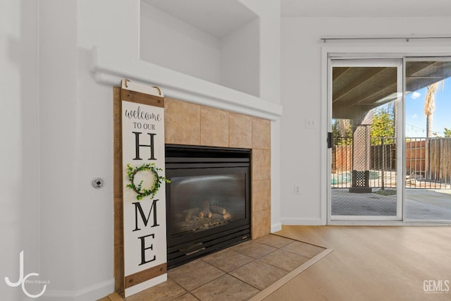 interior details with wood-type flooring and a tiled fireplace