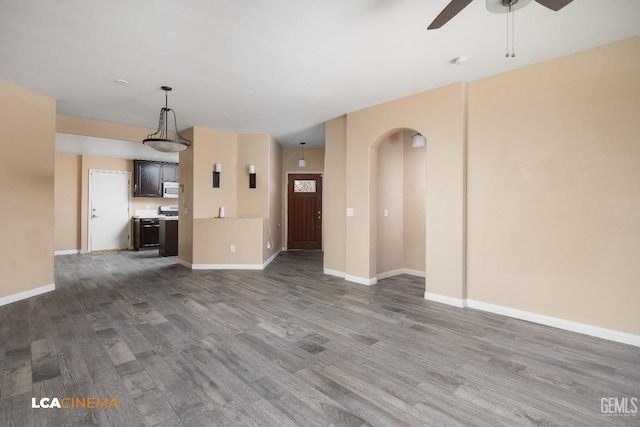 5502 White Pine Way, Bakersfield, CA 93313 - unfurnished living room featuring a ceiling fan, dark wood finished floors, arched walkways, and baseboards