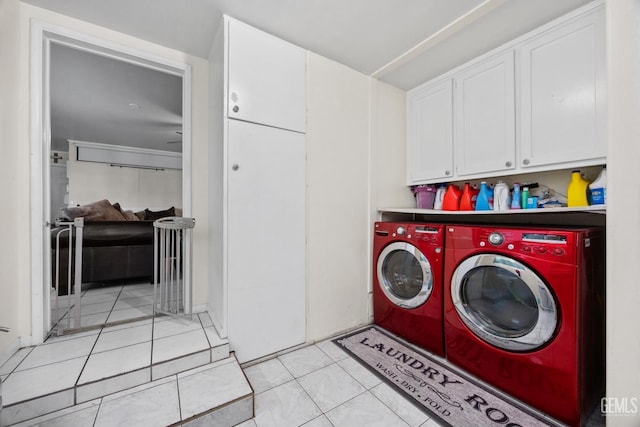 laundry area featuring washer and dryer, cabinet space, and light tile patterned flooring