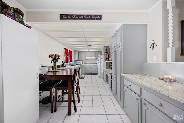 kitchen featuring white appliances, under cabinet range hood, gray cabinets, and light tile patterned flooring