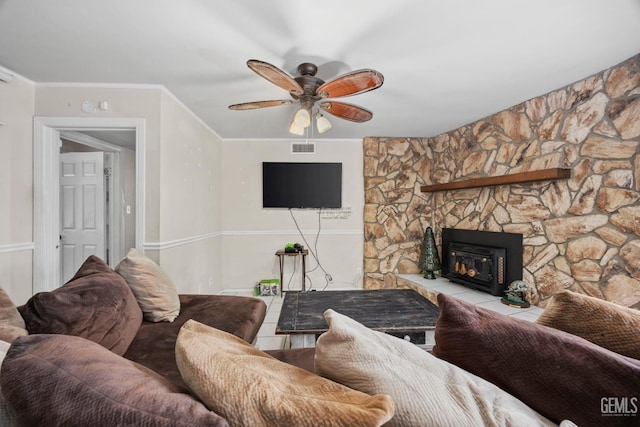 living area with a ceiling fan, a glass covered fireplace, visible vents, and crown molding