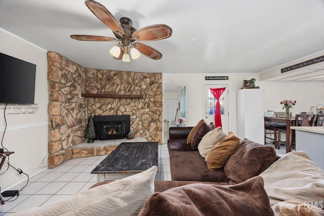 living room featuring light tile patterned floors, ceiling fan, and a stone fireplace