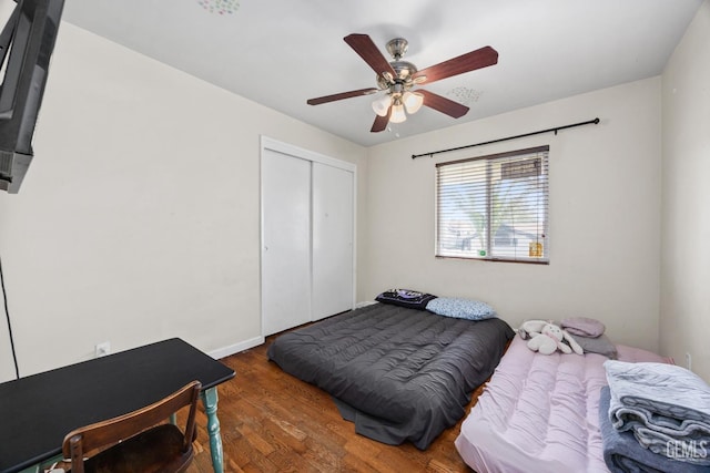 bedroom with dark wood-style flooring, a closet, a ceiling fan, and baseboards