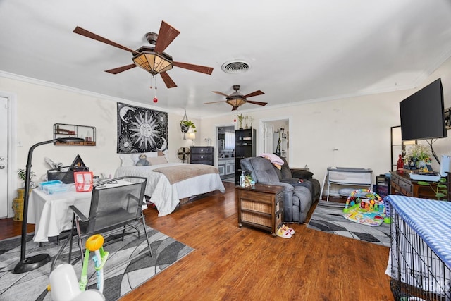 bedroom featuring ceiling fan, wood finished floors, visible vents, and crown molding