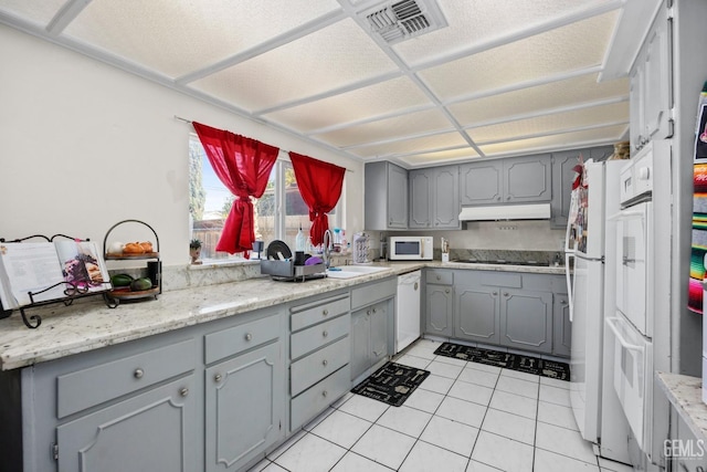 kitchen featuring visible vents, light countertops, a sink, and gray cabinetry