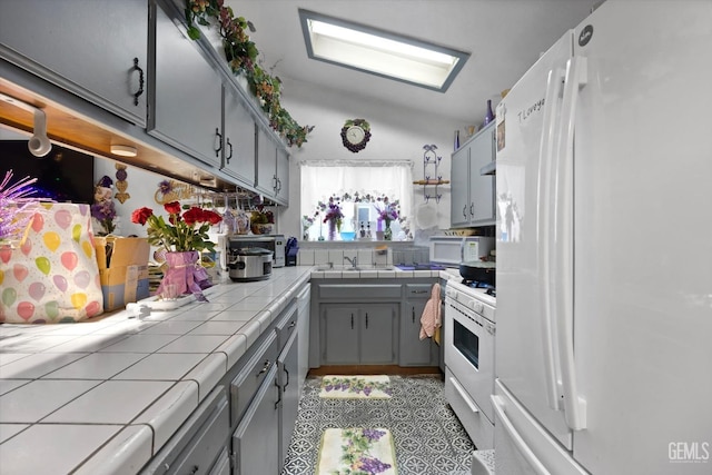 6009 Cedar Glen Ln, Bakersfield, CA 93313 - kitchen with white appliances, tile counters, gray cabinetry, a sink, and vaulted ceiling