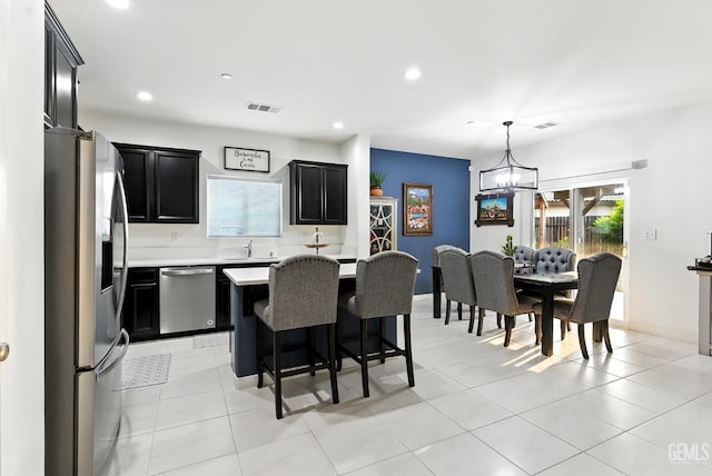 8907 Stevie Ct, Bakersfield, CA 93313 - kitchen featuring appliances with stainless steel finishes, light countertops, dark cabinets, a chandelier, and a kitchen breakfast bar