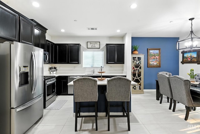 8907 Stevie Ct, Bakersfield, CA 93313 - kitchen featuring stainless steel appliances, dark cabinets, light countertops, a kitchen bar, and a chandelier