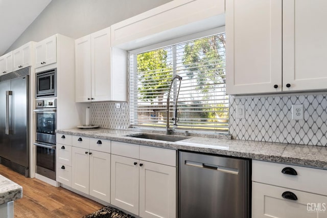 812 Mazatlan Dr, Bakersfield, CA 93314 - kitchen with built in appliances, white cabinets, decorative backsplash, lofted ceiling, and light wood-style floors