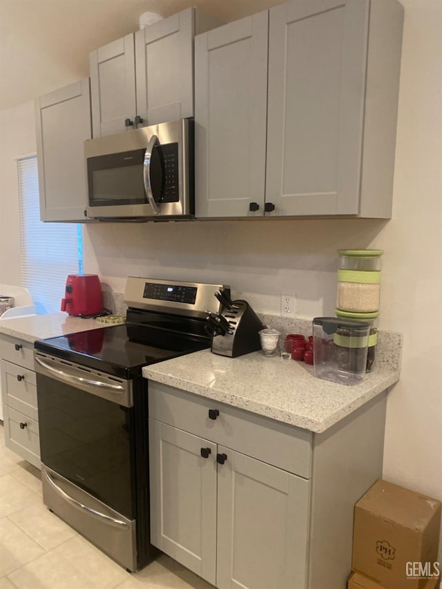 kitchen featuring light stone countertops, light tile patterned flooring, and appliances with stainless steel finishes