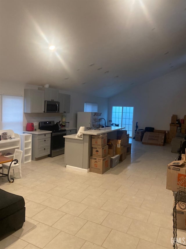 kitchen featuring gray cabinets, light tile patterned flooring, lofted ceiling, and appliances with stainless steel finishes