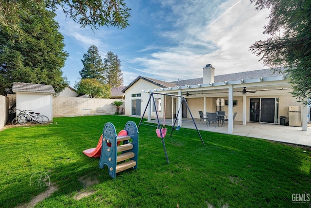 back of house featuring a playground, a yard, and a patio