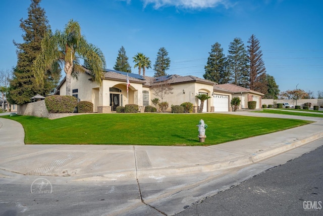 mediterranean / spanish-style house with solar panels, a garage, and a front yard