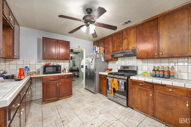 2110 Center St, Bakersfield, CA 93305 - kitchen featuring appliances with stainless steel finishes, a ceiling fan, under cabinet range hood, and decorative backsplash