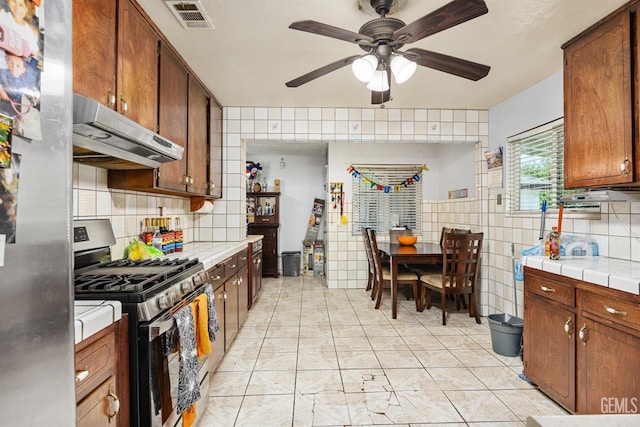 2110 Center St, Bakersfield, CA 93305 - kitchen with stainless steel appliances, under cabinet range hood, ceiling fan, tile walls, and tile countertops