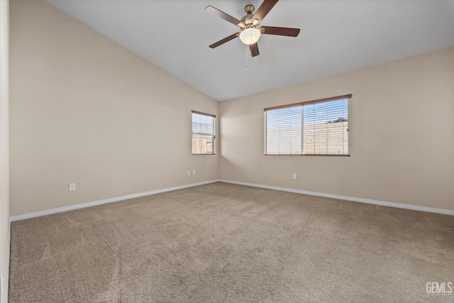 carpeted empty room with vaulted ceiling, ceiling fan, and baseboards