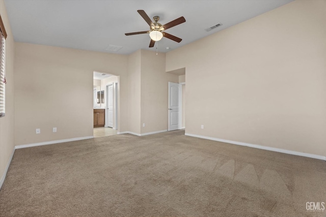 unfurnished bedroom with lofted ceiling, light colored carpet, visible vents, connected bathroom, and baseboards