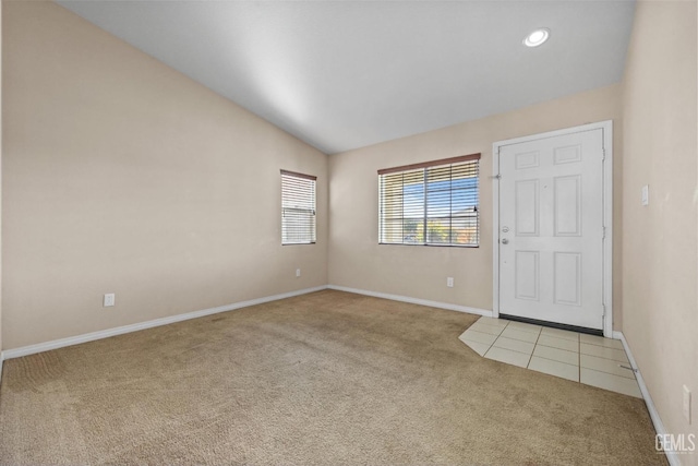 entryway with light carpet, baseboards, and lofted ceiling