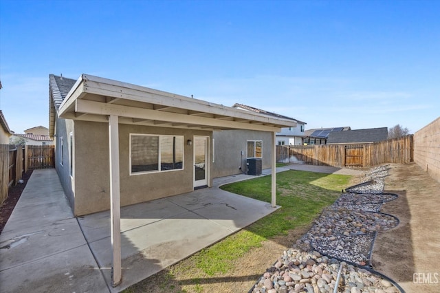 rear view of property with a fenced backyard, a patio, and stucco siding