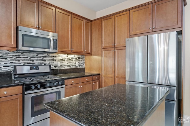 kitchen with appliances with stainless steel finishes, brown cabinetry, decorative backsplash, and dark stone counters