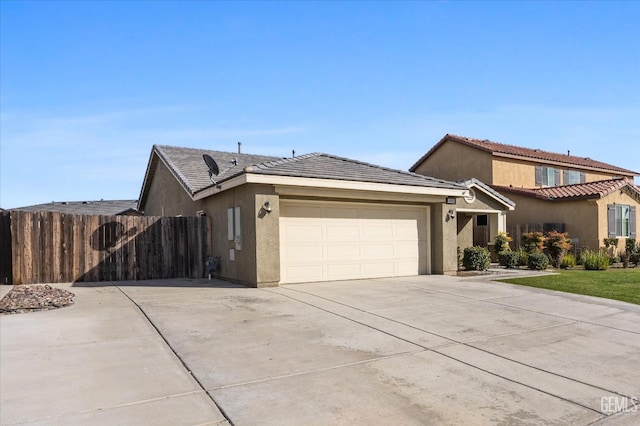 view of front of home with concrete driveway, a tiled roof, an attached garage, fence, and stucco siding