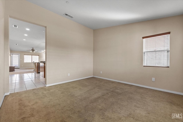 unfurnished room with light tile patterned floors, baseboards, visible vents, and light colored carpet